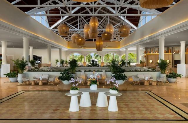 Open-air lobby lounge with a vaulted timber roof and woven pendant lights