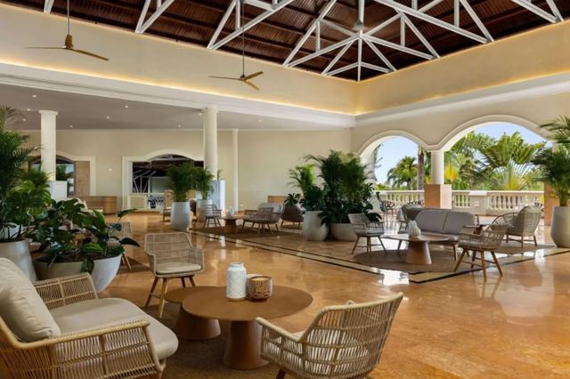 Lobby seating area with wicker chairs, plants and arched garden views