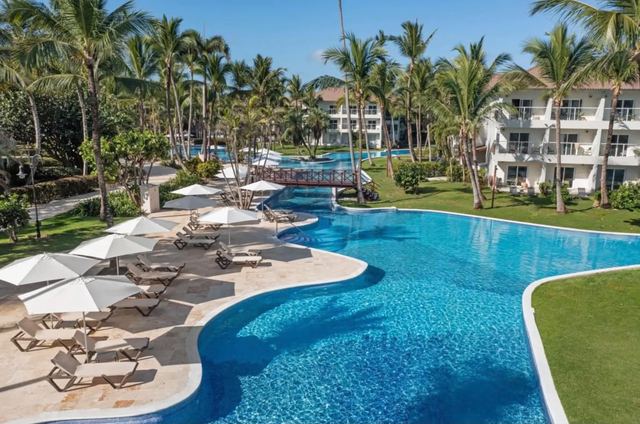 Winding pool lined with sun loungers, umbrellas and palm trees