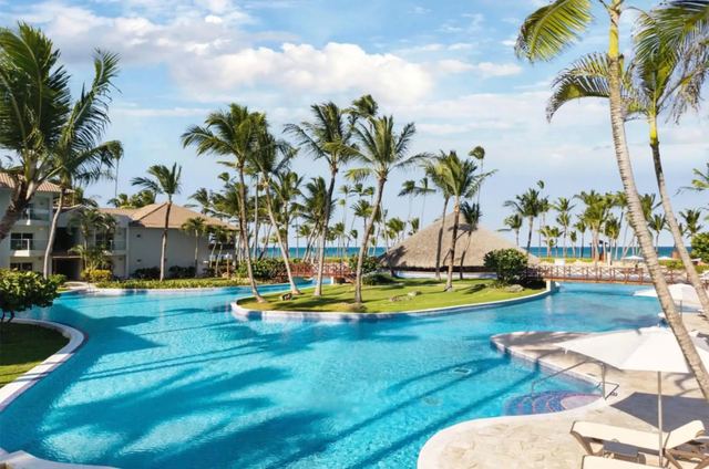 Resort pool with a palm-covered island and the sea beyond