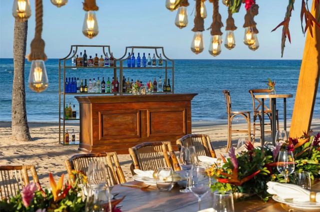 Beach bar on the sand with hanging lights and a set dining table by the sea