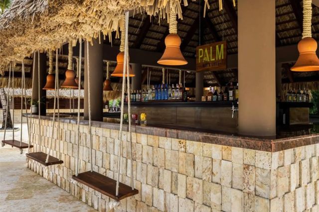 Palm bar with a thatched roof, stone counter and swing seats